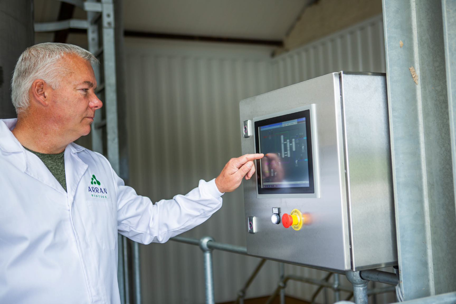 Man in white lab coat touching monitor